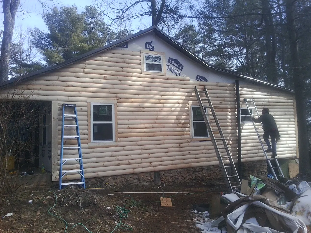 Ladders set against fresh log siding during an exterior remodel in Wantagh
