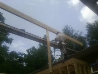 Carpenter setting a ridge beam over a new addition frame — Ice Dam Removal by Roofing Brothers in Wantagh