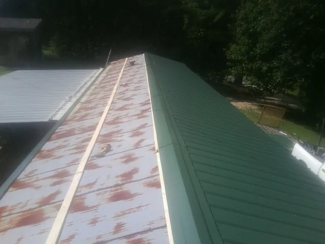 Old rusted panels beside newly installed green metal roofing — Wind Damage Roof Repair by Roofing Brothers in Wantagh