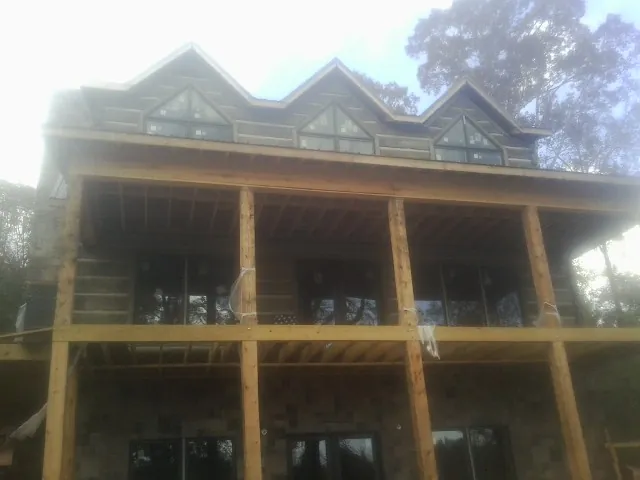 Dormers and porch framing on a large log home under construction — Roof Coating work by our crew in Wantagh