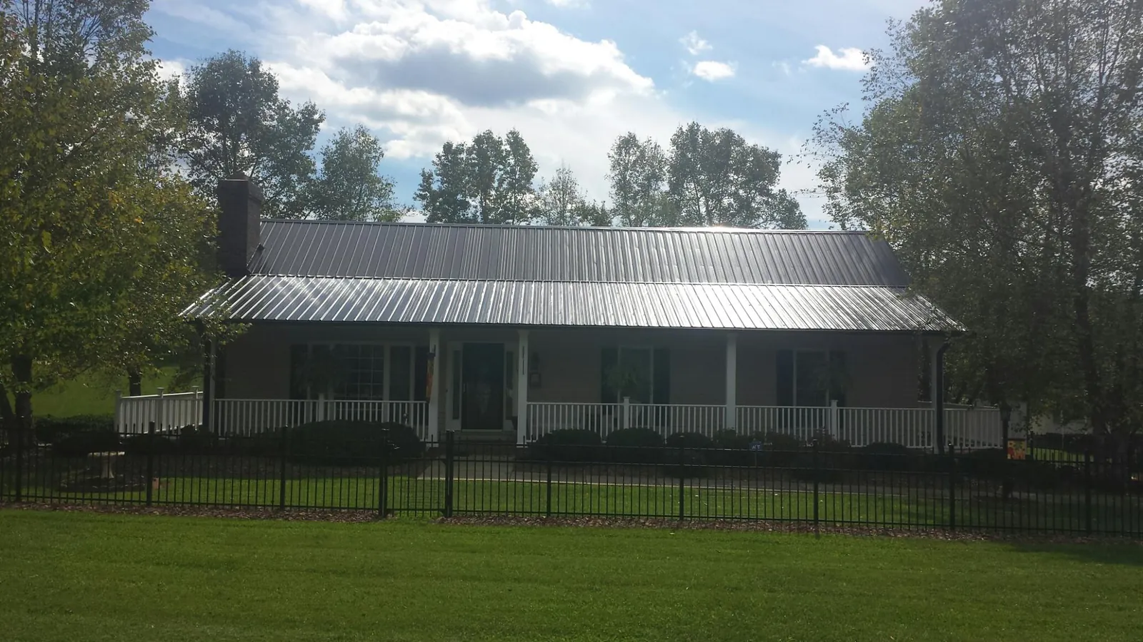 Gray metal roof on a brick ranch with a full width front porch — Gutter Guard Installation work by our crew in Wantagh