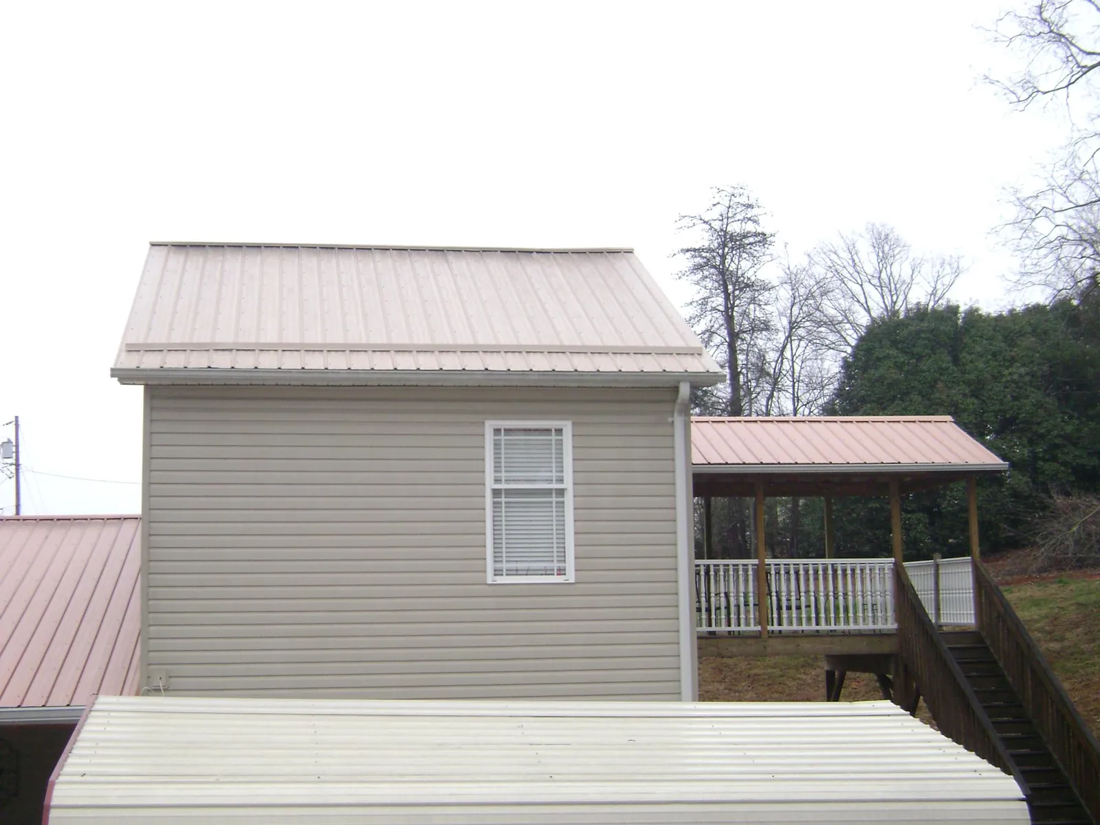 Tan metal roofs on a two story addition and attached porch, from a Roof Replacement job in Wantagh